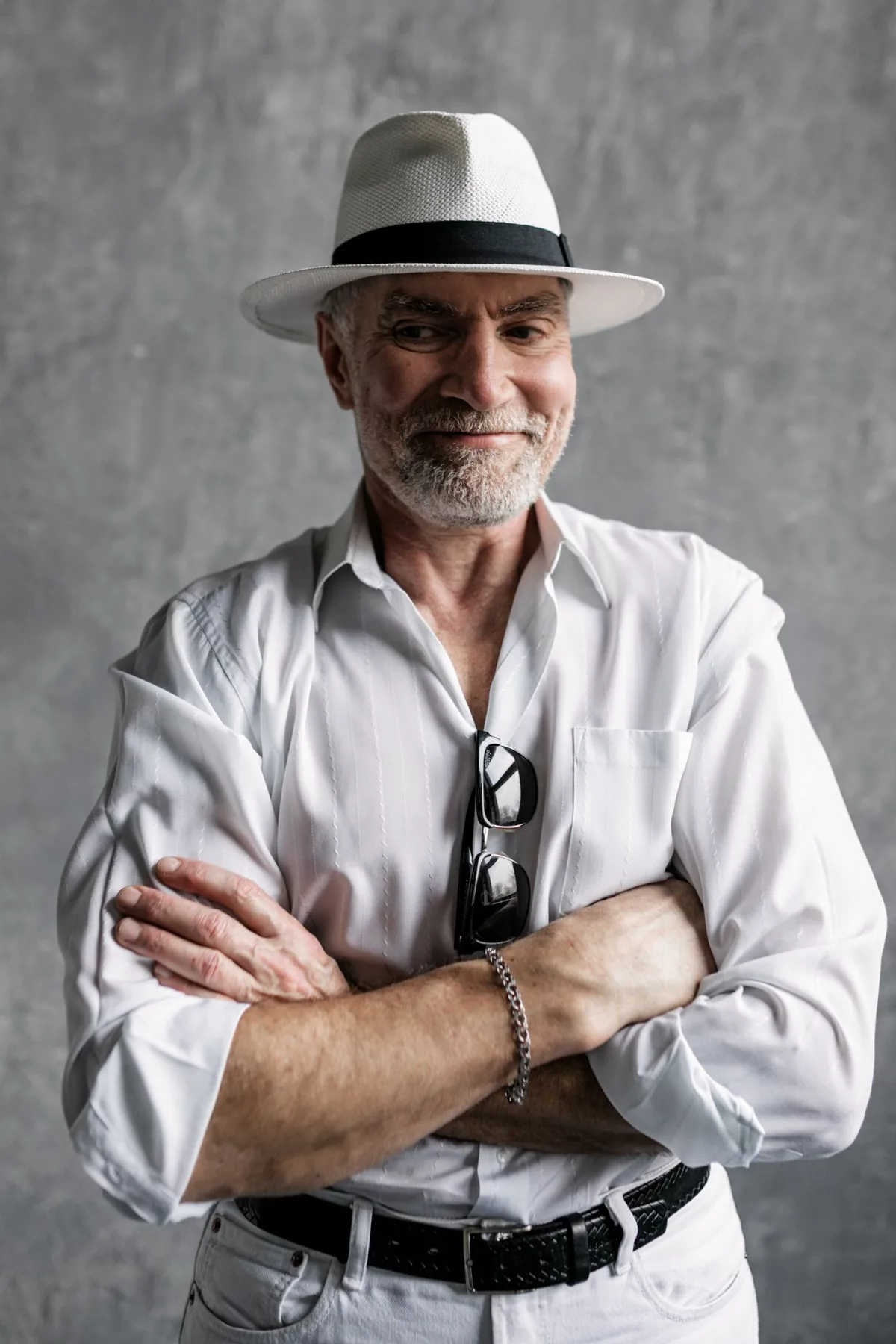 A man in a hat and scarf standing with his arms folded